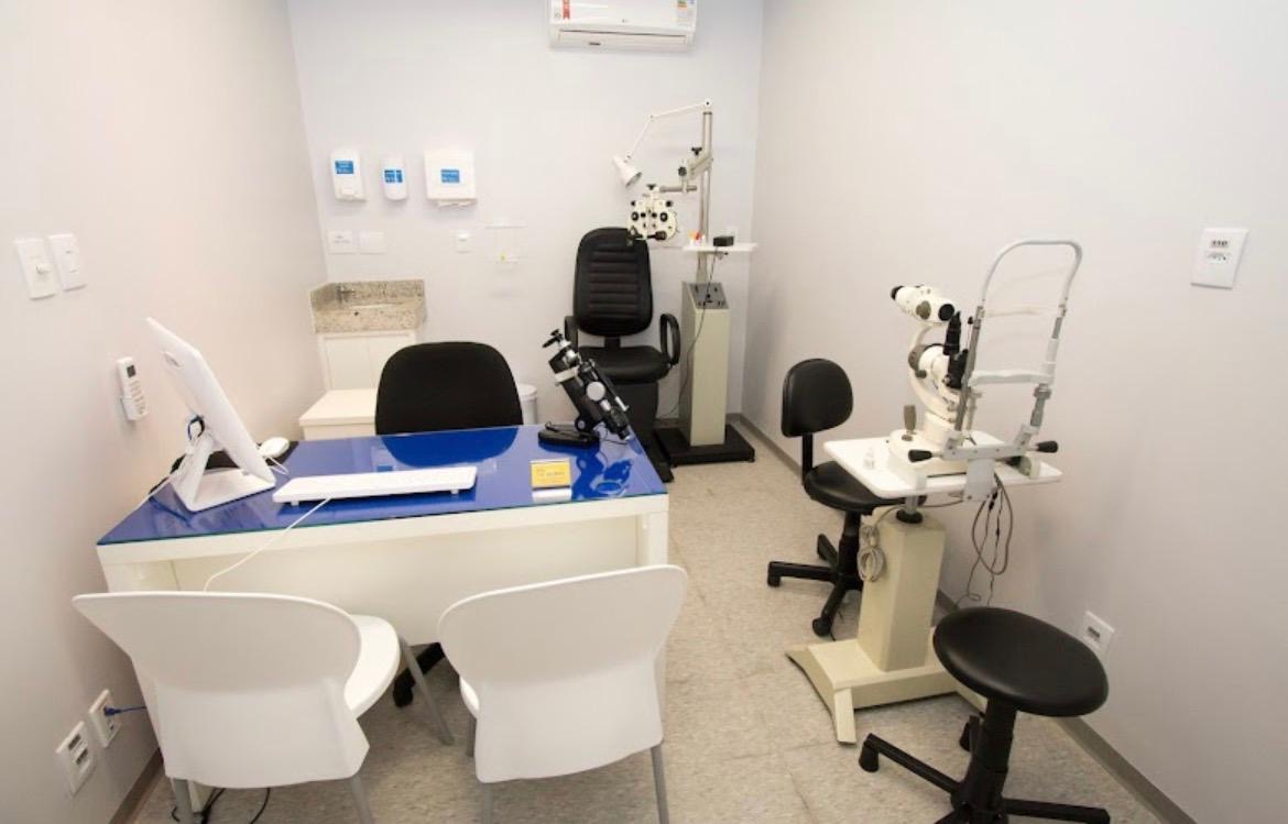 Sala de consulta da Clínica do Bem com equipamento de oftalmologia, lâmpada de fenda e mesa azul